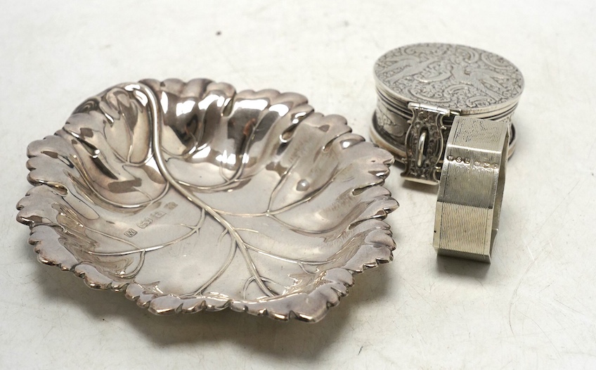 A Victorian silver circular case and cover, containing a collapsible beaker (now detached from the base), by Thomas Johnson I, London, 1873, diameter 53mm, together with a silver napkin ring and modern silver leaf dish.